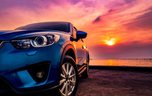 Blue compact SUV car with sport and modern design parked on concrete road by the sea at sunset. Environmentally friendly technology. Business success concept. New Car features 2020